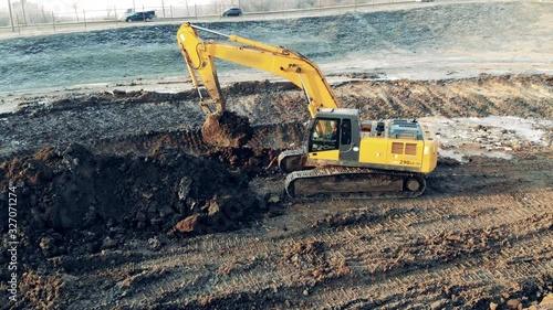 Excavator is digging ground next to the motorway