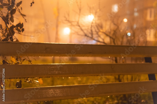 Evening and drops. Bench in the rain. Wet wooden bench.
