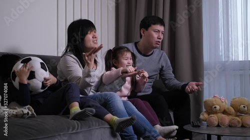 Close-up of excited chinese family with little kids upset with favorite football team losing while watching match on TV at home. Sad soccer fans disappointed during football game photo