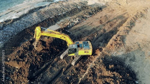 Shoveling machine is grabbing and relocating soil