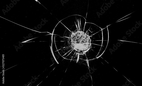 Round white cracks in glass on black background.