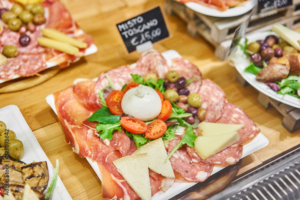 Meat plate, delicacy and Anantipasto. Salami, roast beef, Parma ham, smoked duck breast. Various snacks and antipasti on the table. Street food market in Florence, Italy. Meat plate, delicacy and Anantipasto. Salami, roast beef, Parma ham, smoked duck breast. Various snacks and antipasti on the table. Street food market in Florence, Italy.