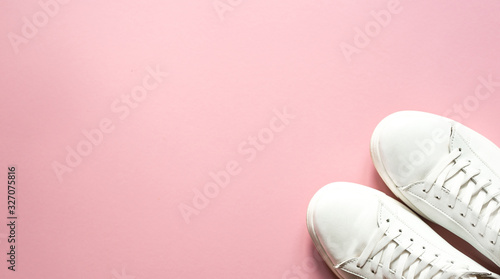Sneakers white over pastel pink   background with top view and copy space. A fashionable but also sporty background. FLATLAY