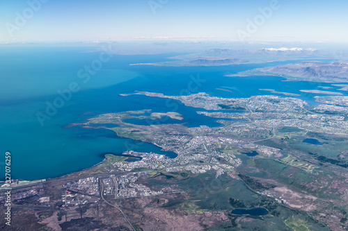 Keflavik, Iceland airport and city bird's eye aerial high angle view of Reykjavik from airplane window above and colorful ocean water