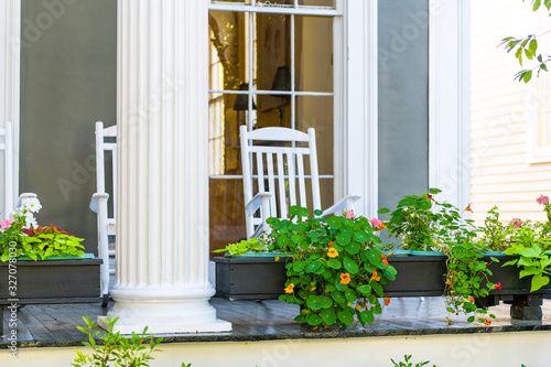 Historic Garden district in New Orleans, Louisiana with patio garden green plants flowers on white antebellum column and rocking chairs on old street photo