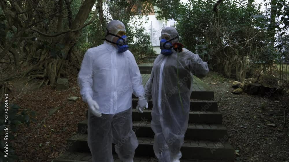 man and woman in hazmat suits and respirator in the Park. the man gives a flower man and woman in hazmat suits and respirator in the Park. the man gives a flower