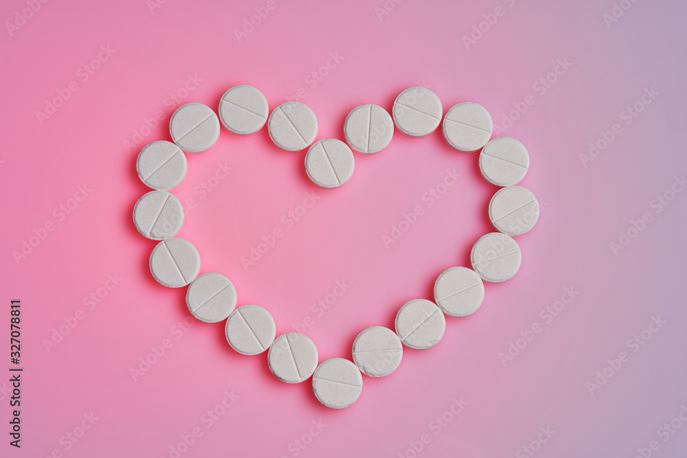 Medicines for the heart lie on a pink background. Heart pills and a bottle lie on a hot pink background.