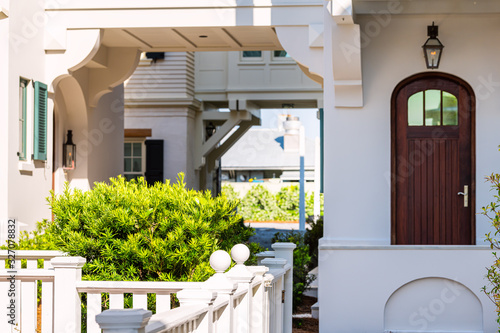 Seaside white beach wooden wood architecture door and path way with green landscaping shrubs bushes on sunny day