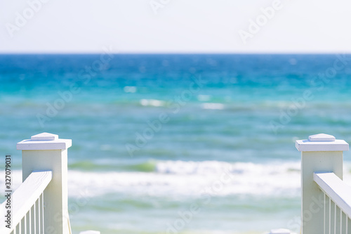 Seaside, Florida white railing wooden stairway walkway down view of architecture by beach ocean background view during sunny day and horizon photo