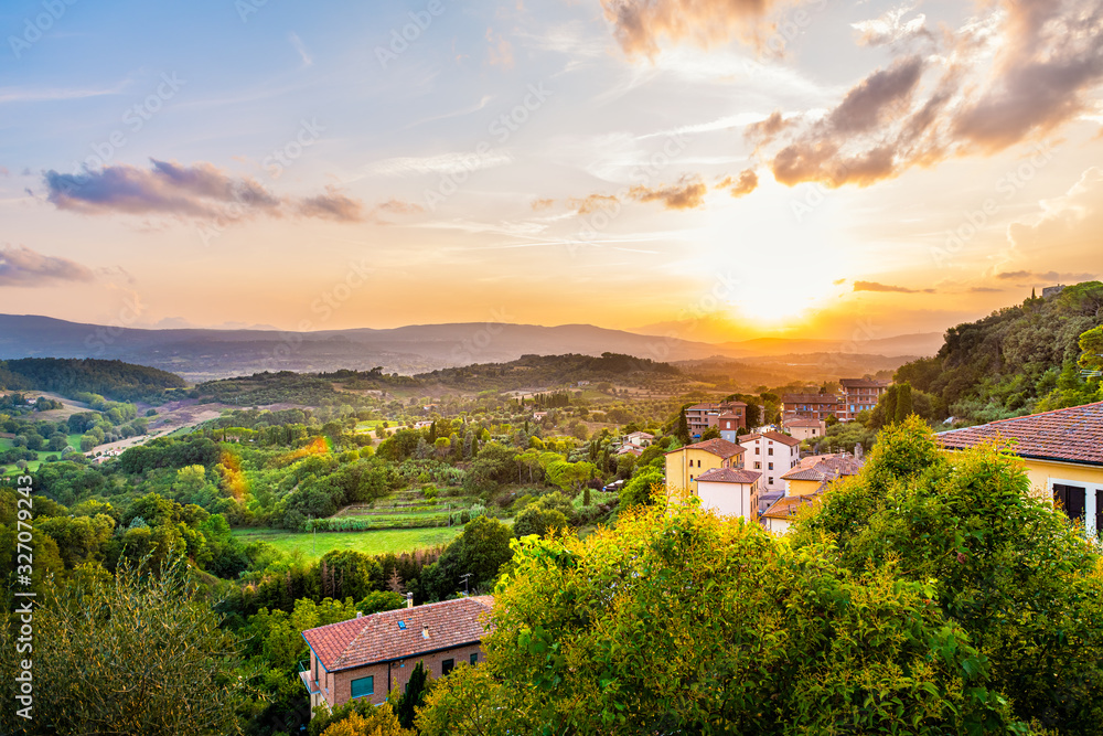 Colorful evening sunset in small town of Chiusi, Tuscany Italy with houses roof rooftops on mountain countryside rolling hills landscape and picturesque cityscape with sun