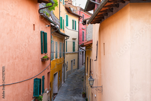 High angle aerial view on Chiusi, Italy street narrow alley in small historic town village in Umbria on sunny day with orange yellow bright vibrant colorful walls, windows shutters photo