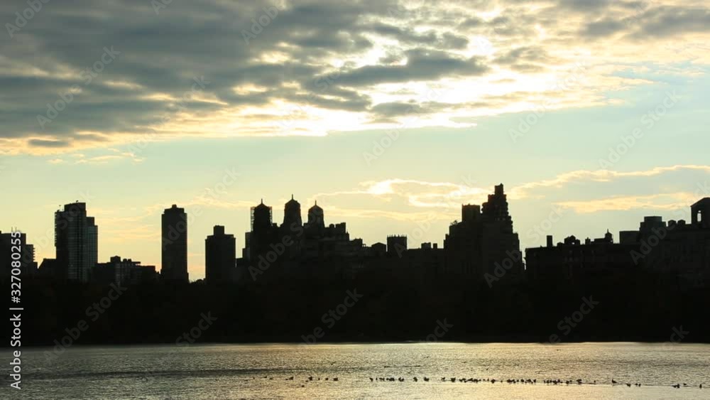 Sky, Clouds and Central Park Reservoir glow and illuminate by sunset. Central Park West Residences become silhouettes. Image was captured from Central park. Sky, Clouds and Central Park Reservoir glow and illuminate by sunset. Central Park West Residences become silhouettes. Image was captured from Central park.