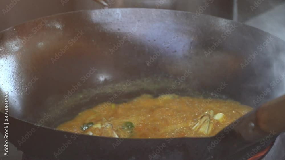 Malaysian male seller cooks crab in curry sauce in a large frying pan at the night market in Kota Kinabalu, Borneo Island, Malaysia, close up Malaysian male seller cooks crab in curry sauce in a large frying pan at the night market in Kota Kinabalu, Borneo Island, Malaysia, close up