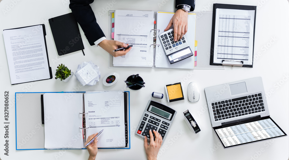 Two Businesspeople Calculating Bills In Office Two Businesspeople Calculating Bills In Office