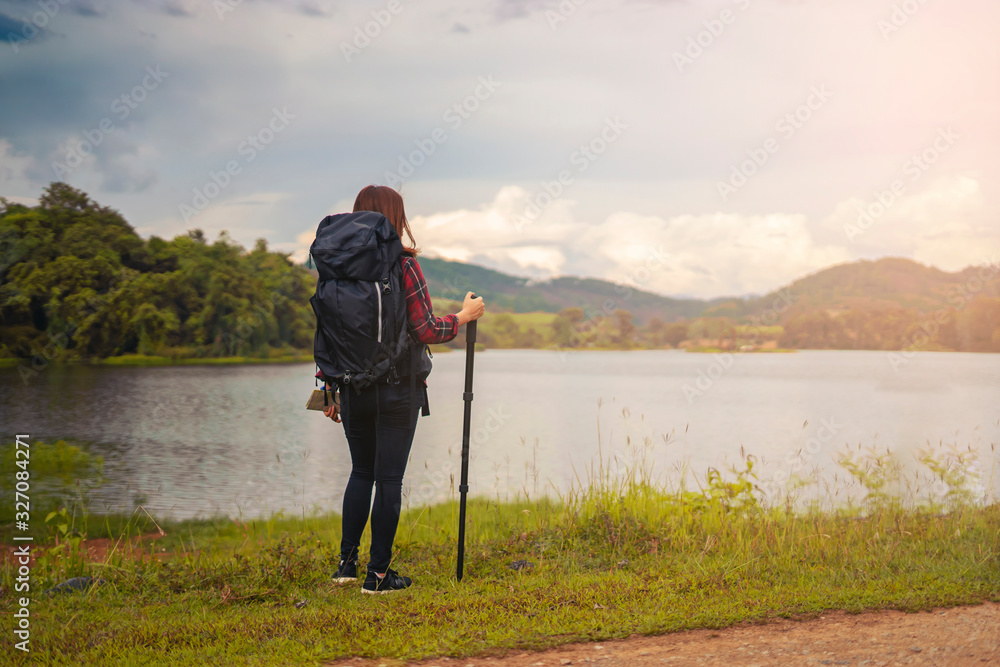 Asian woman traveler with backpack looking at amazing mountains river wanderlust and forest, Traveling tropical  travel concept, copy space for text, see the beautiful natural landscape in Thailand
