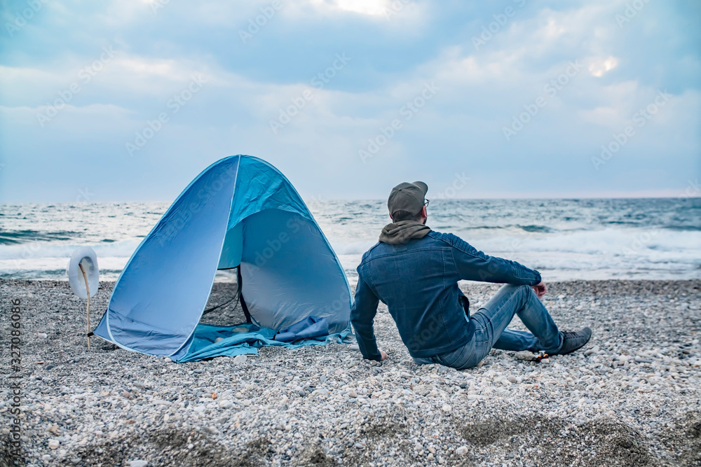 Tourist near his camp tent on against the sea