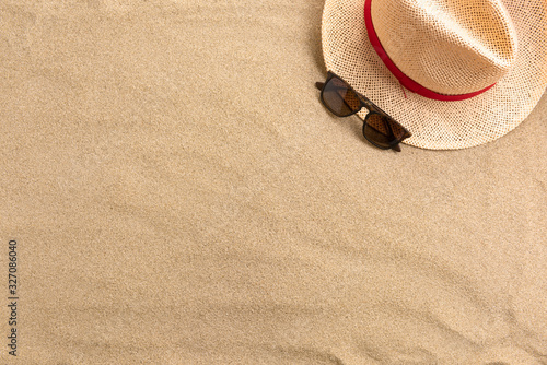 Straw hat and sunglasses, on sand background. Beach vacation concept .Top view with copy space.