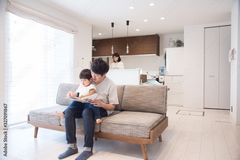 リビングで本の読み聞かせをする父親 リビングで本の読み聞かせをする父親