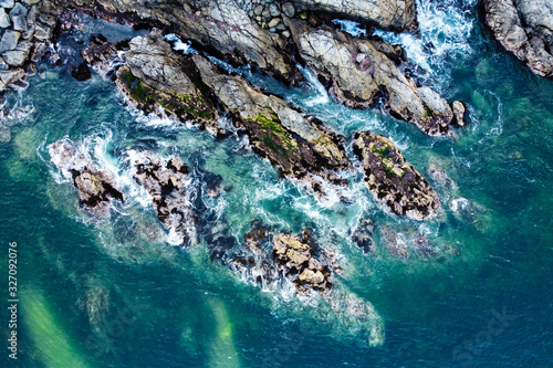 Aerial view of ocean waves and rocky coast. Danger sea waves crashing of huge rocks with spray and foam. Valparaiso, Chile.