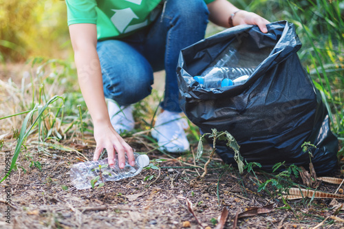 Canvas Print Closeup image of a woman picking up garbage plastic bottles into a bag for recyc