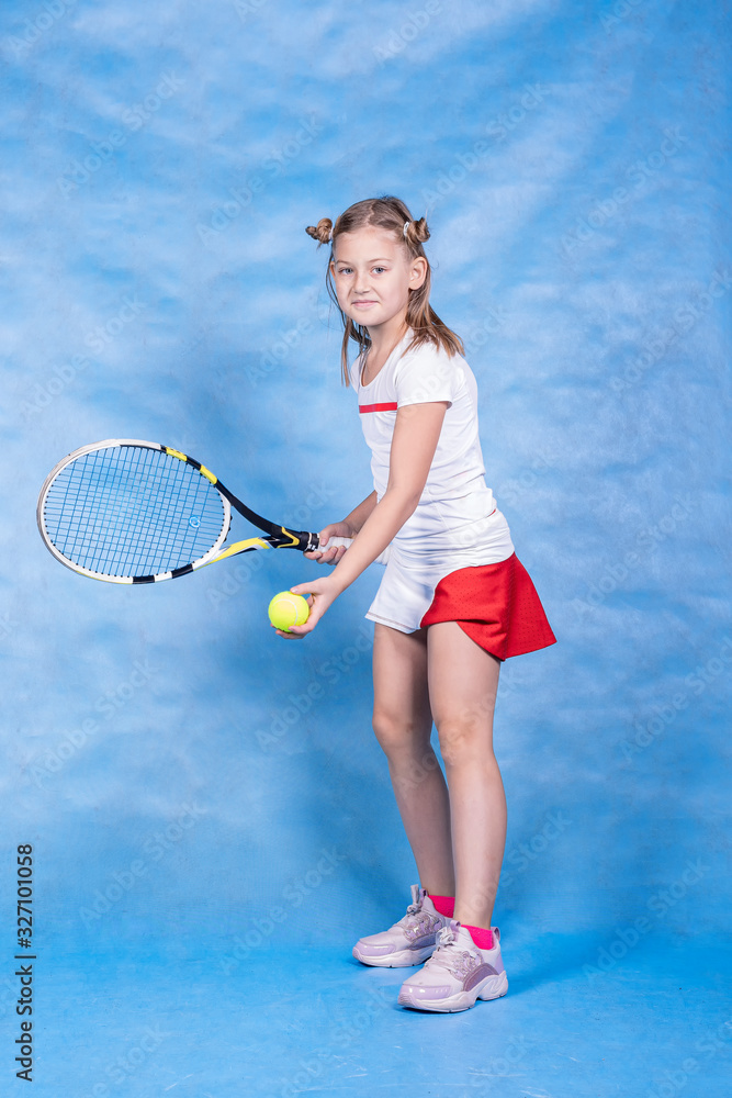 Young tennis player warming up before the game on a blue background. Tennis, reception, children’s sports.