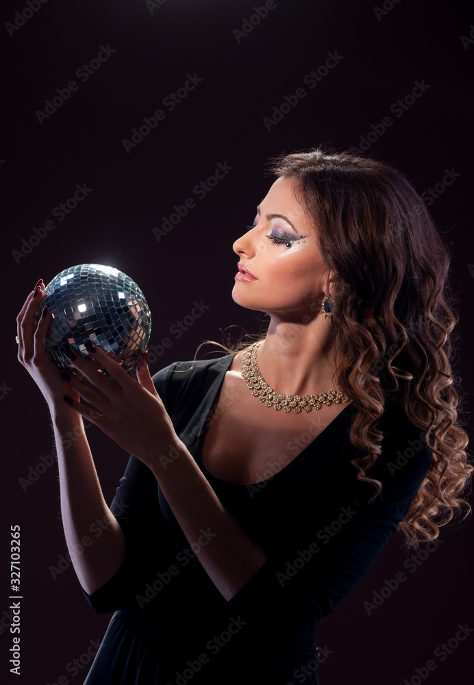 Naklejka premium Girl with a shiny ball on a dark background..