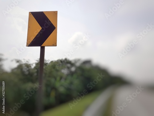 Black colour right curve sign on yellow plate at the highway
