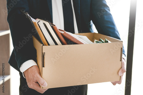 Sad Fired Young Employee businessmen hold boxes including pot plant and documents for personal belongings unemployment, resigned concept. photo