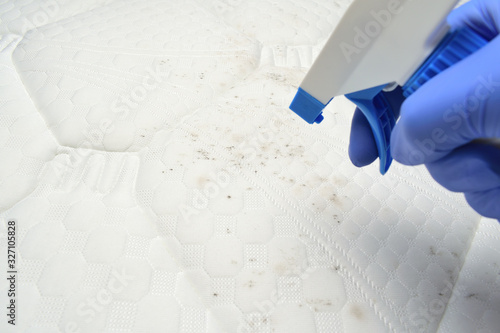 Foam cleaner spray. Cleaning a mattress cloth with a liquid stain remover. Hand pulls a trigger.