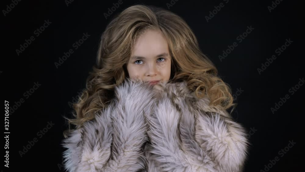 Little girl model poses and looks camera. Portrait of confident preschool child in modern stylish clothes on black background. Beauty face of innocent small fashion person, luxury kid with curly hair Little girl model poses and looks camera. Portrait of confident preschool child in modern stylish clothes on black background. Beauty face of innocent small fashion person, luxury kid with curly hair