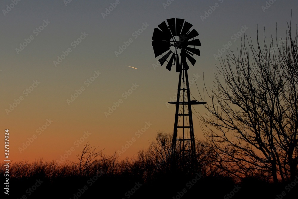Kansas colorful Sunset with tree's,clouds, and a Windmill silhouette north of Hutchinson Kansas USA out in the country. Kansas colorful Sunset with tree's,clouds, and a Windmill silhouette north of Hutchinson Kansas USA out in the country.