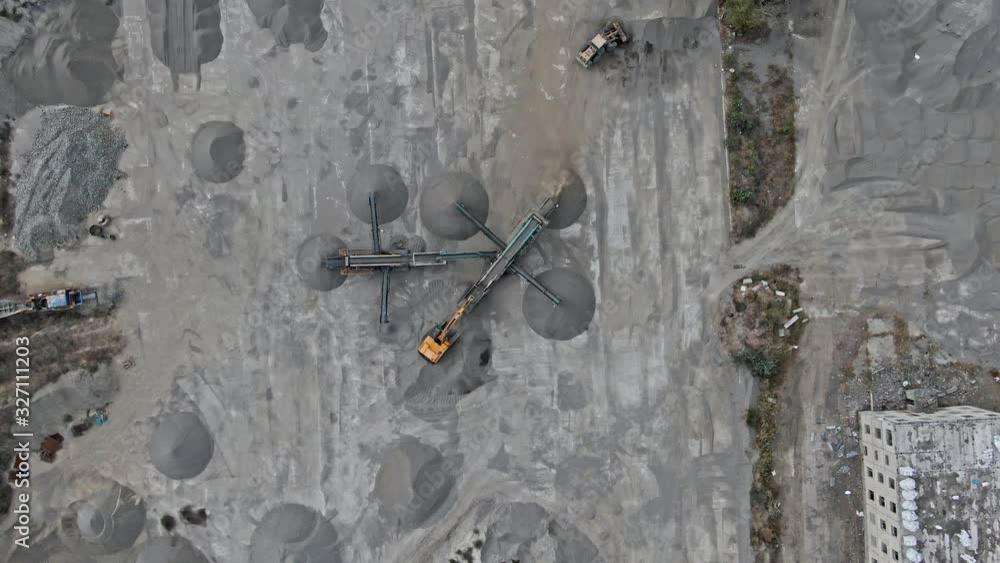 AERIAL SHOT Mobile mini dressing area at a construction site. stone crusher The process of crushing crushed stone into different fractions and sorting into heaps. Excavator and grader operation AERIAL SHOT Mobile mini dressing area at a construction site. stone crusher The process of crushing crushed stone into different fractions and sorting into heaps. Excavator and grader operation