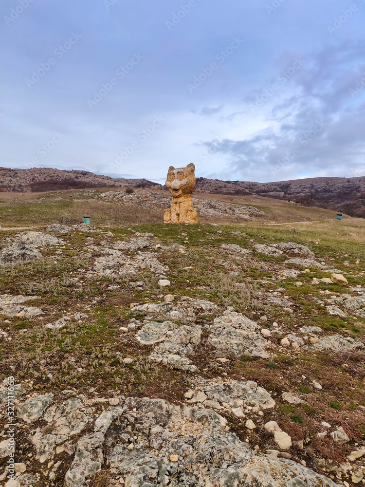 stone cat stands on a hill on the road to the mountains