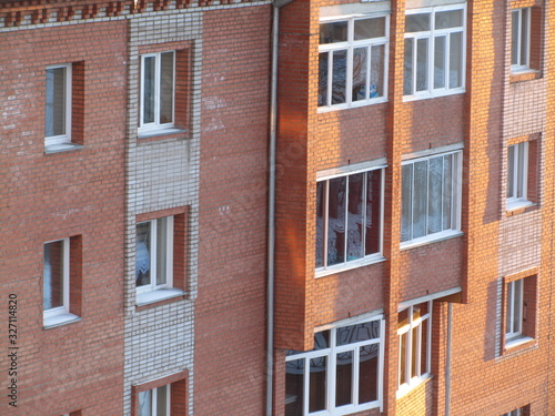 Modern brick residential building close-up. Perspective view of a house wall with windows and balconies. Facade of a brick urban apartment building. © Наталья Босяк