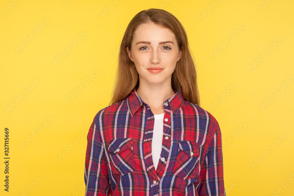 Portrait of happy attractive ginger girl in checkered shirt standing, looking at camera with positive cheerful expression, clean face skin, beauty care. studio shot isolated on yellow background Portrait of happy attractive ginger girl in checkered shirt standing, looking at camera with positive cheerful expression, clean face skin, beauty care. studio shot isolated on yellow background