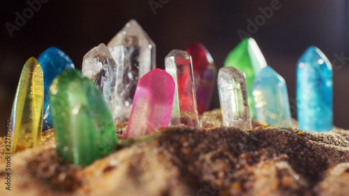 Foto Multicolored crystal quartz sticks of gems protrude from the sand