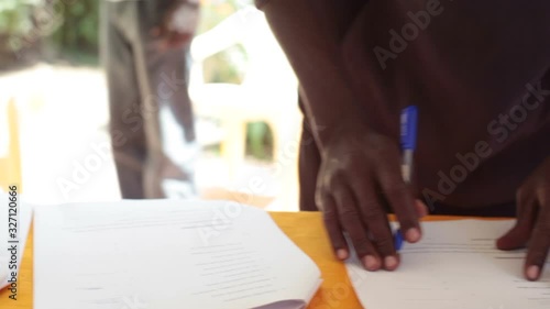 Black man signs paper contract, close up, shallow DOF