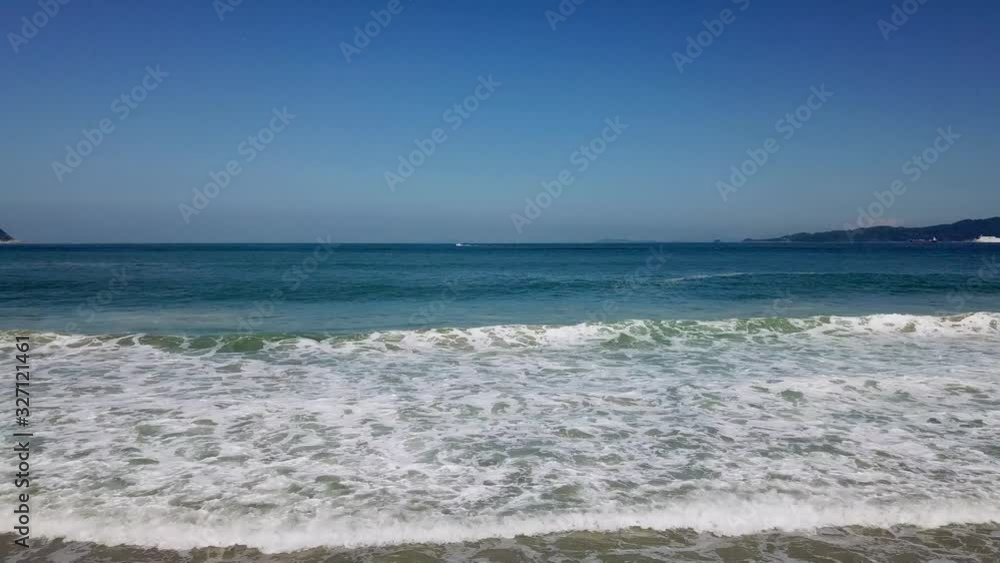 打ち寄せる輝く波 真っ白な泡 青い海と空の背景 左にトラック 打ち寄せる輝く波 真っ白な泡 青い海と空の背景 左にトラック