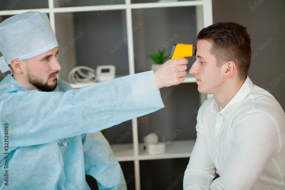 Obraz premium Doctor measures the patient's temperature with a laser thermometer
