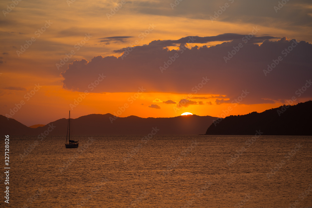 Beautiful orange sunset seascape view with boat and setting sun background Beautiful orange sunset seascape view with boat and setting sun background