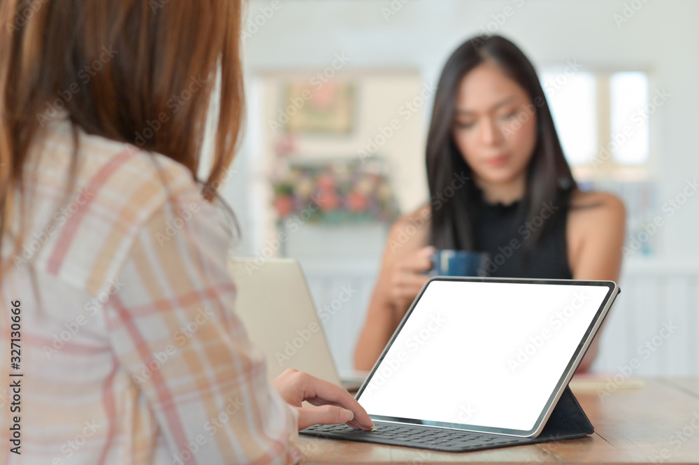 Female employee using a laptop to present the project to the executives sitting with coffee in the back. Female employee using a laptop to present the project to the executives sitting with coffee in the back.