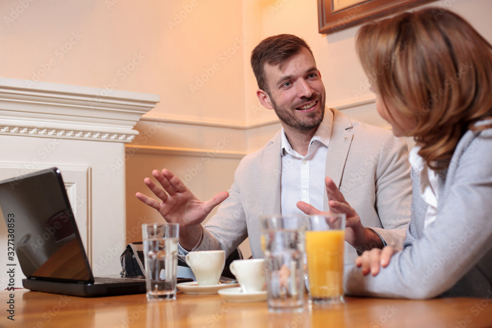 Two smiling caucasian business partners meeting in a cafe during coffee break, talking and discussing Two smiling caucasian business partners meeting in a cafe during coffee break, talking and discussing