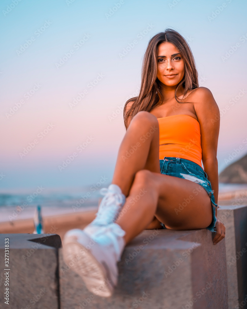 A pretty brunette sitting on a sunset with purple light in the background