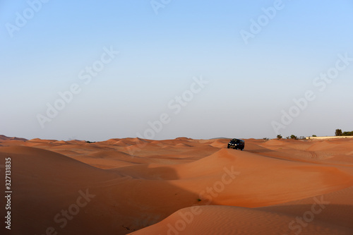 Huge dunes of the desert. Beautiful structures of yellow sand dunes. Offroad vehicle bashing through sand dunes in the desert. United Arab Emirates. Asia.
