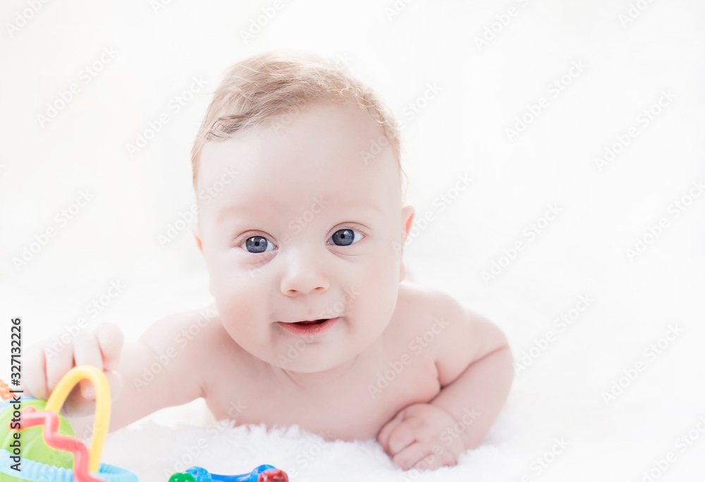 four month old white boy with blue eyes lying on his stomach on a white background four month old white boy with blue eyes lying on his stomach on a white background