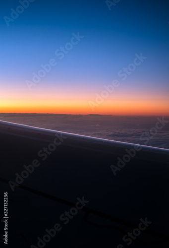 Silhouette airplane wing over the clouds at sunrise