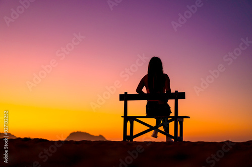 Beautiful silhouette of one in a chair on the beach in a beautiful orange sunset