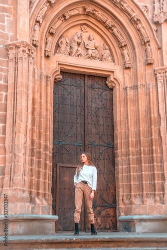 Lifestyle, a young caucasian blonde at the giant door of a church
