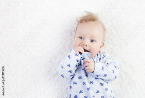 cute baby in blue pajamas with pacifier on a white background