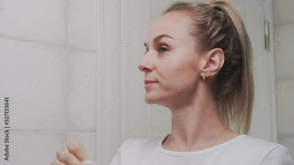 CLose up of woman removes mask on her face looking in mirror CLose up of woman removes mask on her face looking in mirror